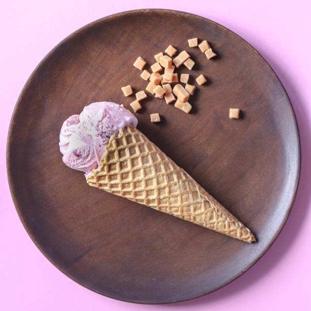 istock Wooden  plate with icecream cone on pink background 1151611306