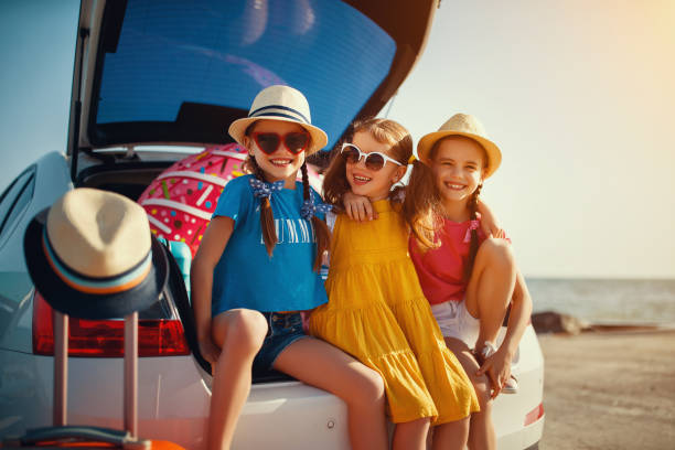 glückliche kinder mädchen freunde schwestern auf der autofahrt zur sommerreise - people child twin smiling stock-fotos und bilder