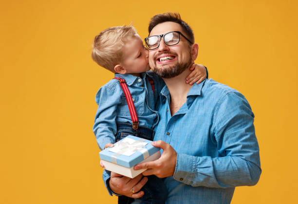 happy father's day! cute dad and son hugging on yellow background happy father's day! cute dad and son hugging on colored yellow background happy fathers day funny stock pictures, royalty-free photos & images