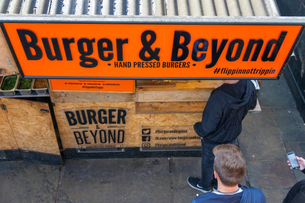 A burger stall at Camden market with queuing customers London, UK - 18 May, 2019 - A burger stall at Camden market with queuing customers camden stables market stock pictures, royalty-free photos & images