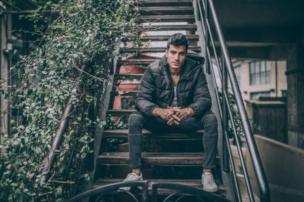 istock Man sitting on stairs, looking at camera 1151622844