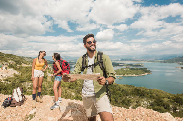 istock Happy man hiking with friends and checking a map. 1151623086