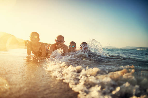 Father and kids having fun in sea Father and kids playing in sea on sunset. They are laughing as the waves are splashing them.
Warm summer sunset.
Nikon D850 girls laying on beach stock pictures, royalty-free photos & images