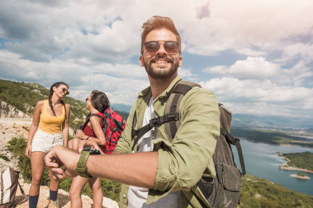 istock Happy young man hiking with friends and using a smart watch. 1151628540
