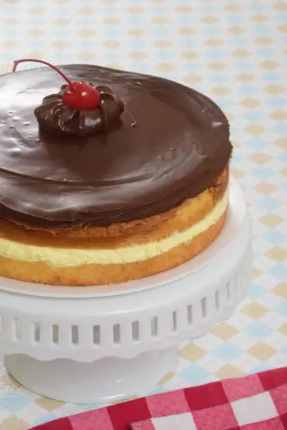 Classic American dessert - Boston Cream Pie which is actually a layered cake with vanilla sponge cake, pastry cream or custard, and chocolate icing.