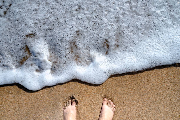istock Feet on a fine sandy beach with waves on the background 1151639240