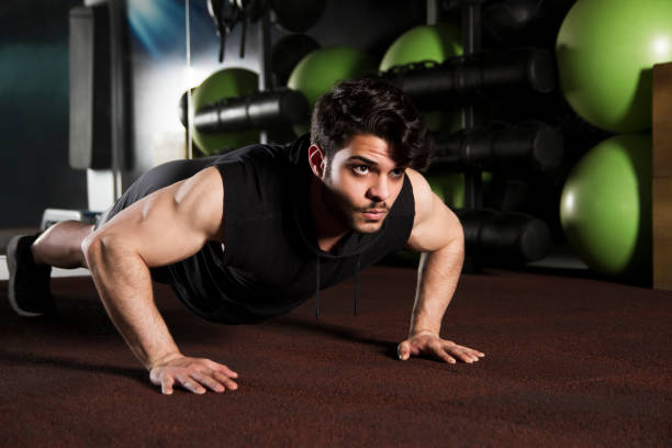 istock Young Trainer Doing Push-ups on Gym Floor 1151640616