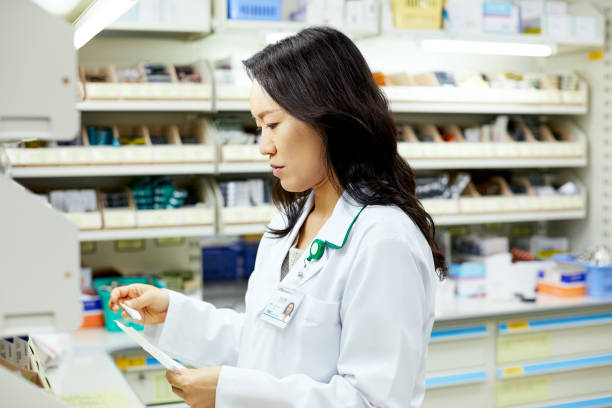 Confident female chemist examining drug at store Confident chemist examining drug at medical store. Female healthcare worker is at pharmacy. She is in lab coat. healthcare and medicine business hospital variation stock pictures, royalty-free photos & images