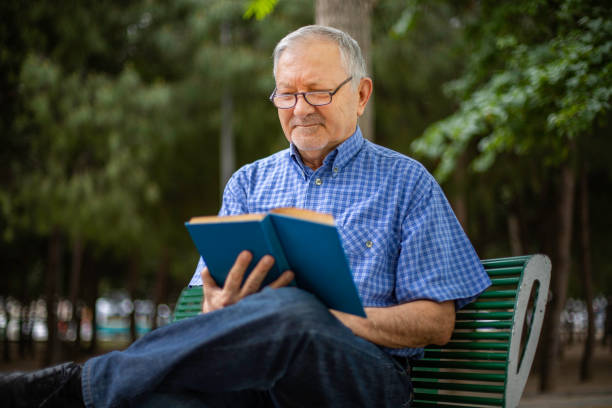 istock An old man is sitting on the bench and reading a book 1151643949
