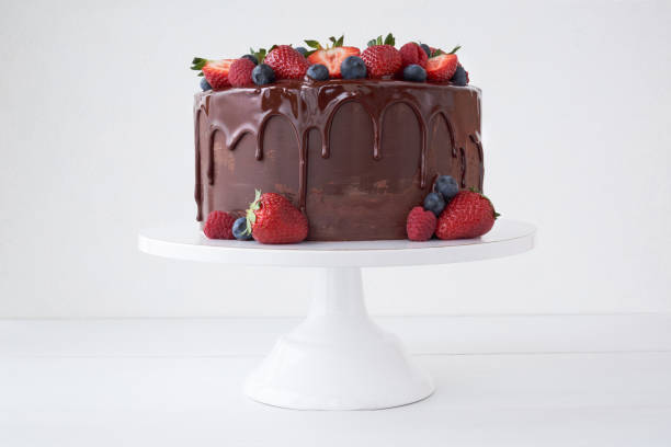 istock Cake with chocolate, decorated with various berries on a white table. 1151647145