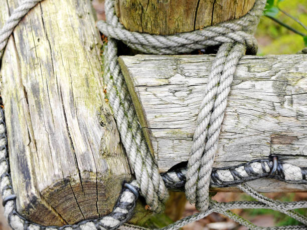 istock White ropes connecting several wooden beams or balks with knots forming a fence. 1151660607