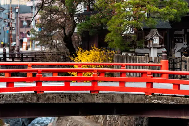 Small red vermillion bridge by Enako river in Takayama, Gifu prefecture in Japan with yellow tree and lantern