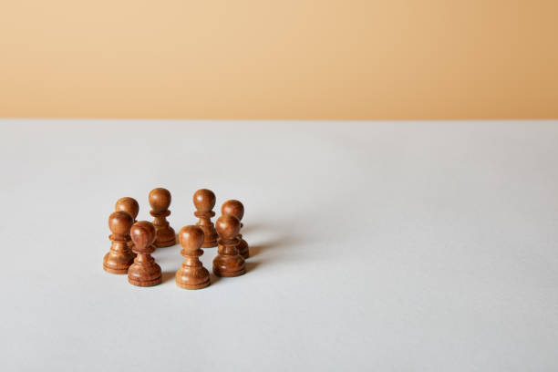 istock wooden pawn pieces on white table and beige background 1151664112