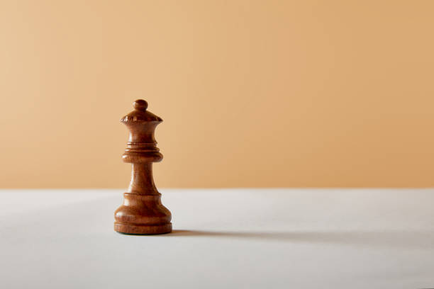 istock wooden queen piece on white table and beige background 1151664128