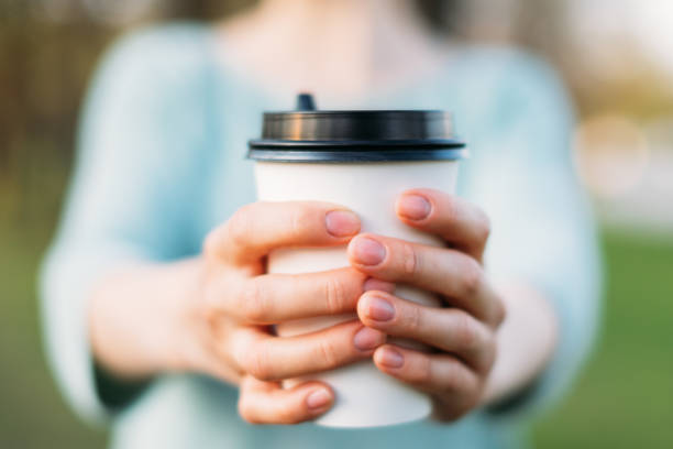 istock Woman in turquoise sweater extend hands forward with the disposable coffee cup mockup. 1151668558