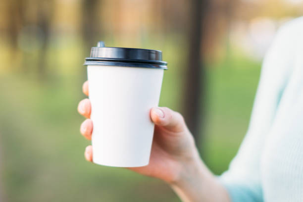 istock Female hand keeping disposable cup mock up in park in summer. 1151668562