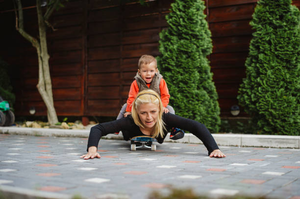 istock Young mother playing with her little boy on a skateboard 1151673143