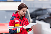 Concentrated female paramedic in uniform using digital tablet