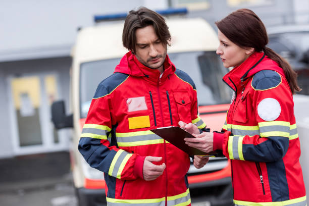 istock Serious paramedics in red uniform reading notes in clipboard 1151675447