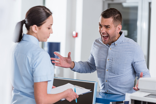 Hombre agresivo gritando a la enfermera en la clínica photo