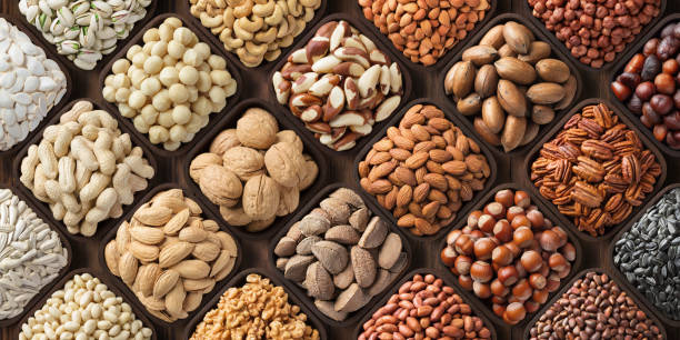 assorted nuts background, large mix seeds. raw food products: pecan, hazelnuts, walnuts, pistachios, almonds, macadamia, cashew, peanut and other seeds and nuts background, natural food in wooden bowls, top view. cashew photos stock pictures, royalty-free photos & images