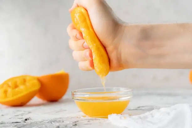 Photo of person squeeze fresh orange juice with a bare hand, healthy drink in a glasss