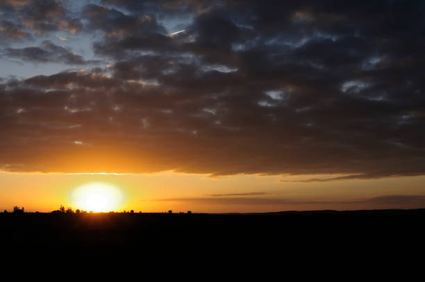 istock Sunset and thunderclouds against the orange sky. The sun has almost disappeared over the horizon. 1151682183