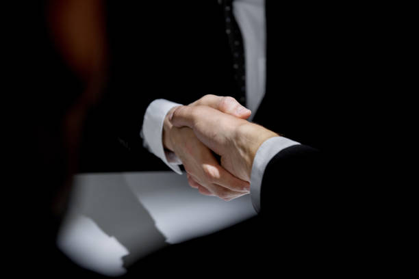 istock Business partners making handshake in dark shadow 1151683293