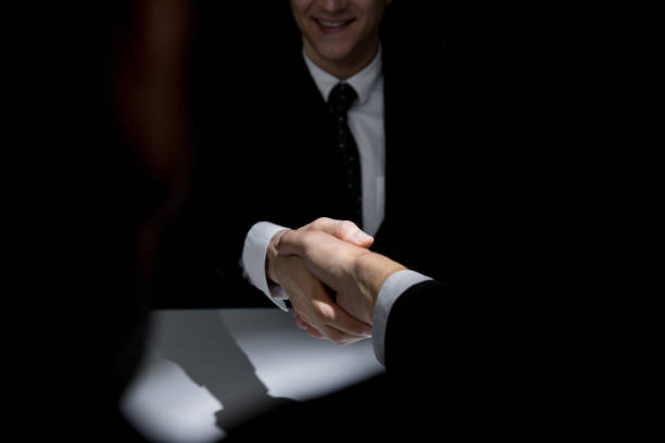 istock Business partners making handshake in dark shadow 1151683296