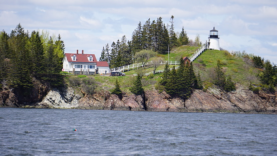 This photo was taken from a wooden sailing boat.  The views that can be expected aboard any nautical vessel off the coast of Maine.  This light house is just one of the many that dot the islands of coastal Maine.