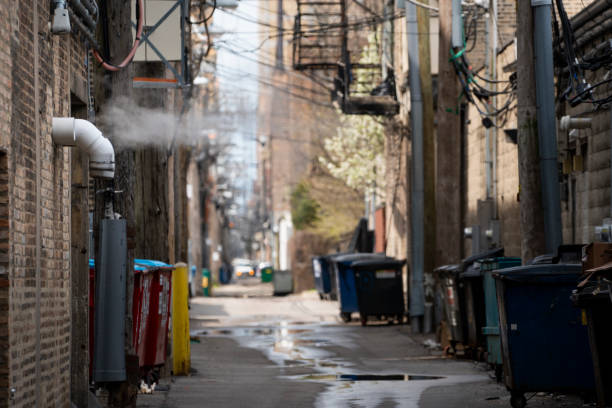 Alley with steam vent and puddles A steam vent blurs the skyline in a shadowed alleyway. seedy alley stock pictures, royalty-free photos & images
