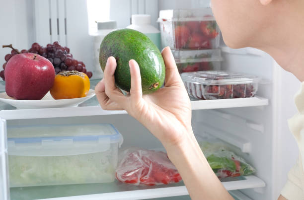Men selection ingredients for good health, Holding an avocado make a health food. Health care by eat clean food consist of Fruits, Vegetable, Apple , Strawberry and Tomato and Grape inside the fridge. stock photo
