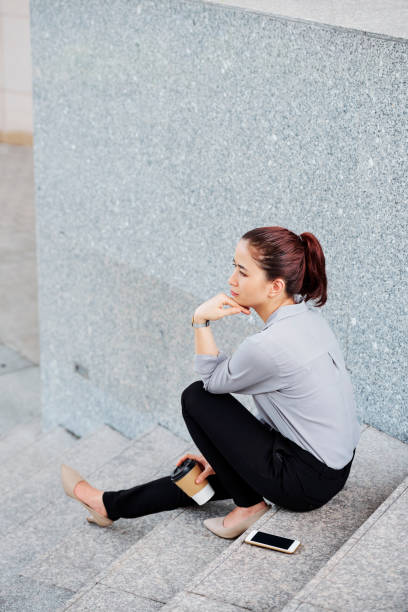 istock Young Asian woman sitting on steps 1151723711