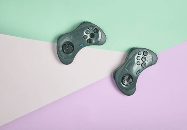 istock Two gamepads on a colored paper background. Top View 1151729798