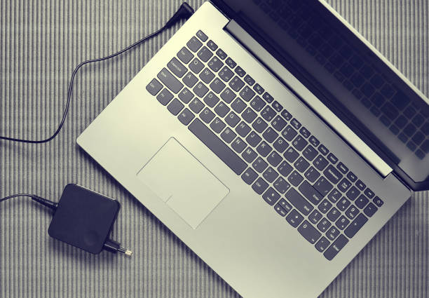 istock Laptop and charging for a laptop on a gray textured background, top view 1151730272