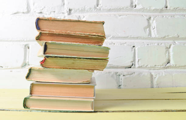 istock Stack of antique books on table against a white brick wall. School concept, education. 1151731070