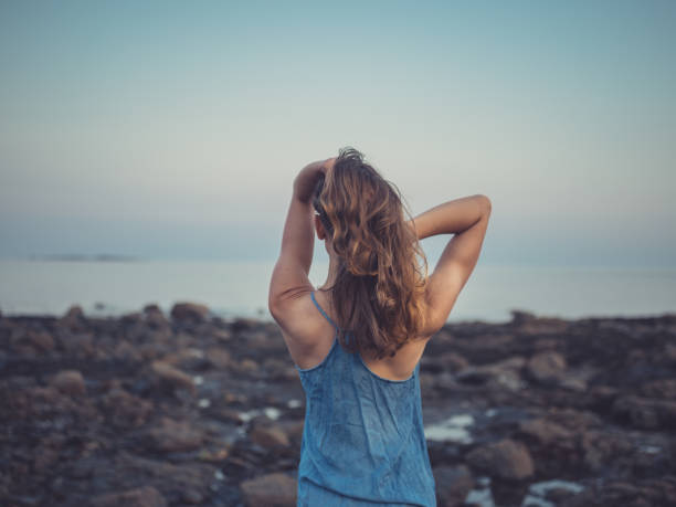 istock Young woman standing on coast at sunset 1151732805