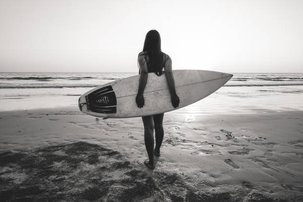 istock woman with surfboard on beach 1151736560