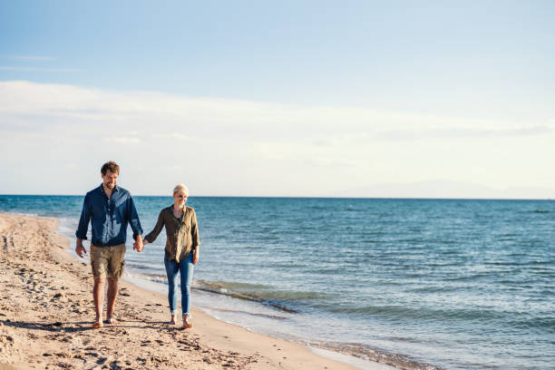 istock Young couple walking outdoors on beach, holding hands. Copy space. 1151737621