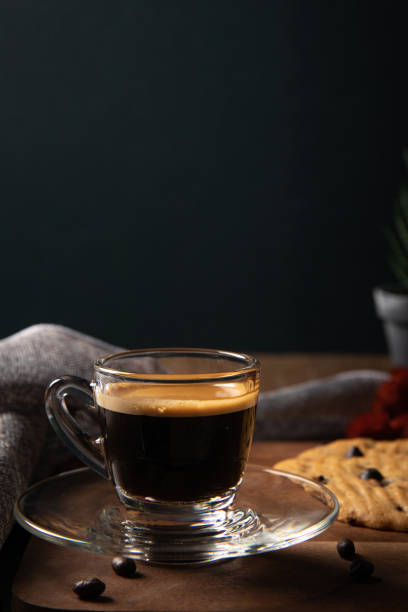 A cup of hot coffee espresso  with coffee bean and homemade cookie on wooden table