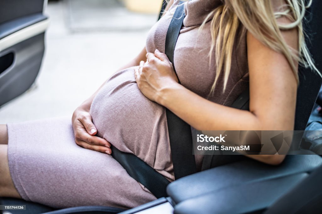 Pregnant woman with safety seat belt Close up pregnant woman’s belly and safety belt in the car. Pregnant Stock Photo
