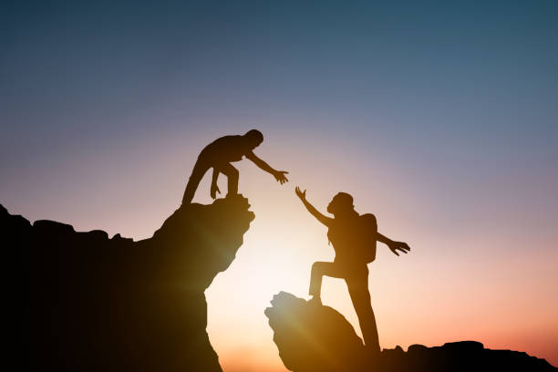 istock help and improve concept, silhouette people helping other hiker climbing rock and mountain 1151745625