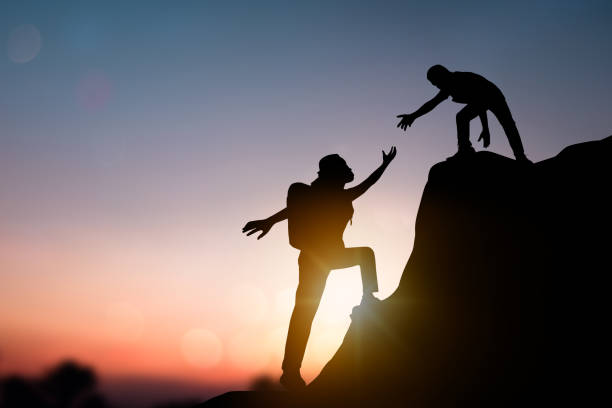 istock help and improve concept, silhouette people helping other hiker climbing rock and mountain 1151745639