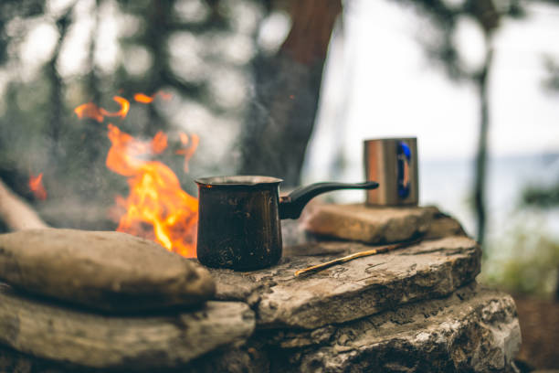 Making coffee in the fireplace when camping or hiking in the nature. Coffee in cezve stock photo