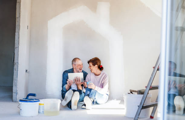 istock Senior couple painting walls in new home, using tablet. Relocation concept. 1151746855