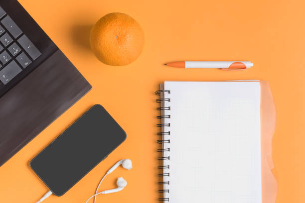 istock Creative concept. Desktop, freelancer, businessman, student. Laptop, workbook, smartphone, pen, orange, headphones on coral background, flat lay. 1151748601