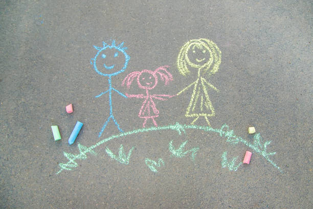 el niño dibuja una familia en el pavimento con tiza. enfoque selectivo. - little girls sidewalk child chalk fotografías e imágenes de stock