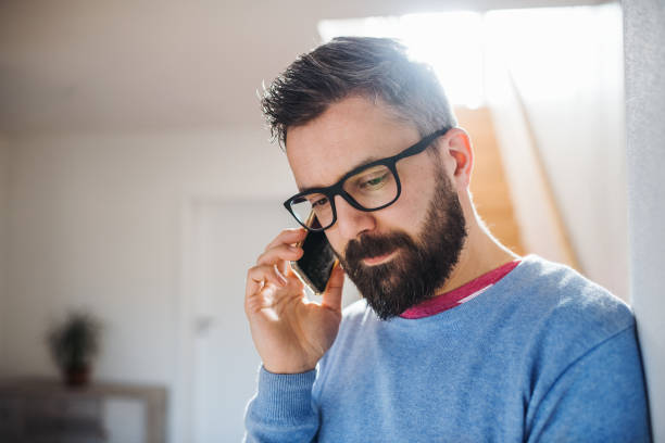 istock A man with smartphone standing indoors at home, making a phone call. 1151752210