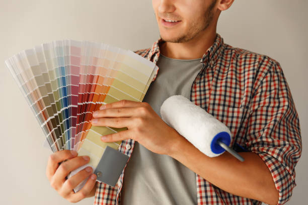 istock Man holding color palette and paint roller and looking to camera 1151766013