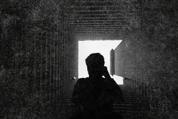 istock Man shadow while take photo in the reflect of Abstract building facade concrete void or tunnel with natural light in the end / architecture design / abstract concept / background texture 1151766213